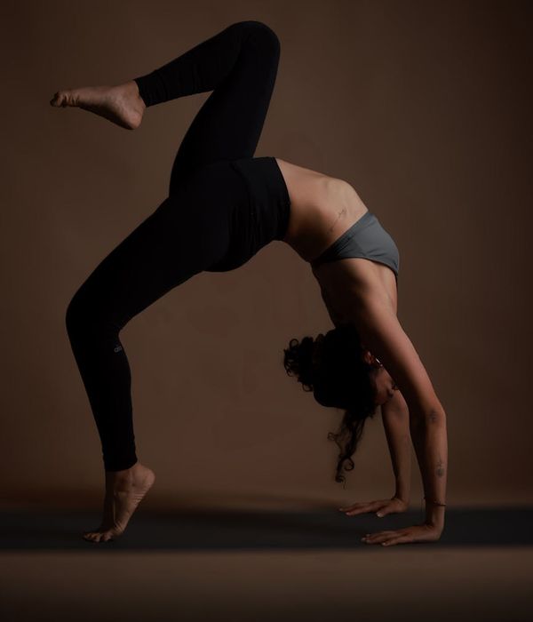 Woman performing a gentle stretching pose in a calm, dark environment.